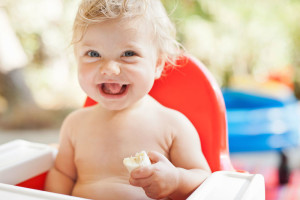 Laughing toddler eating in high chair